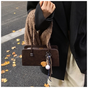 Detalle de bolso boston retro de cuero marrón con colgante de béisbol y adorno de piel suave