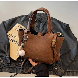 Gros plan d'un sac seau vintage marron en similicuir avec un pendentif de baseball