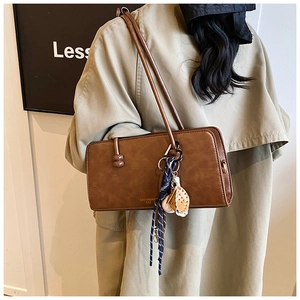 Bolso bandolera marrón vintage en un modelo que lleva una gabardina de color caqui