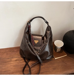 Detail view of vintage dark brown large hobo bag with gold metal logo and woven tassel