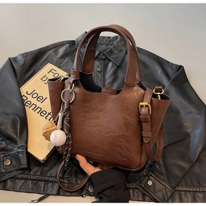 Détail macro du sac seau rétro marron avec texture cuir et pendentif de baseball