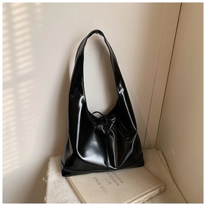 Detail of the black glossy patent leather tote bag featuring elegant bow tie closure