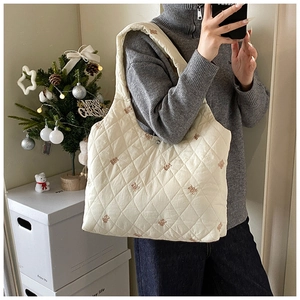 Close-up of quilted cream tote bag with cute bear embroidery and diamond lattice pattern