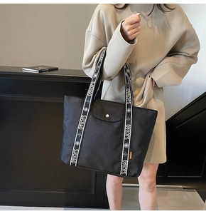 Detail of black fabric tote bag with SJCHAO letter print strap and front flap pocket