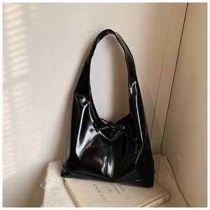 Detailed view of black patent leather hobo bag with a stylish drawstring bow decoration