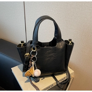 Détail d'un sac seau vintage noir avec breloques de baseball et texture en cuir