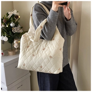 Close-up of cream quilted tote bag with brown bear embroidery and soft fabric texture