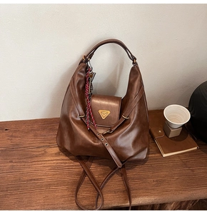 Detail showing deep brown leather texture and metal logo of a vintage hobo bag