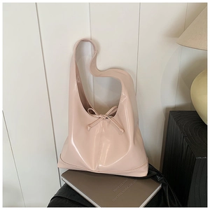 Detail of a pink patent leather hobo bag with a decorative bow in a cozy home setting