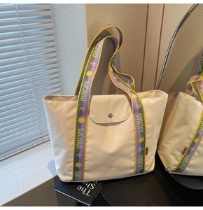 Detail of cream tote bag with stylish purple jacquard shoulder strap and metal snap button