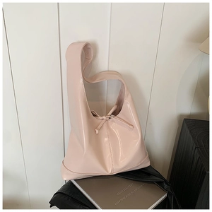 Close-up of pink glossy patent leather tote bag featuring decorative bow and wide handle