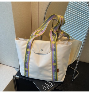 Close-up of large nylon tote bag featuring colorful jacquard straps and metallic snap button