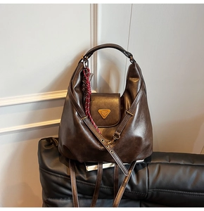Close-up of brown vintage leather hobo bag with gold hardware and silk scarf detail