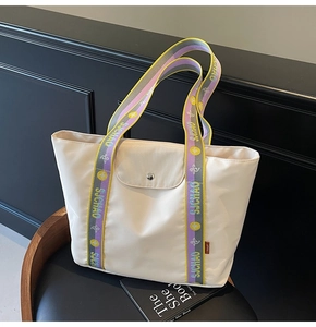 Detail of off-white tote bag featuring colorful SJCHAO logo strap and snap closure