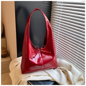Detail of red glossy hobo bag with ribbon bow on a blazer and book background