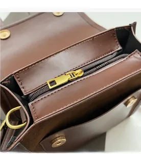 Gros plan sur la texture du cuir contrasté et le zip doré sur le sac à dos marron