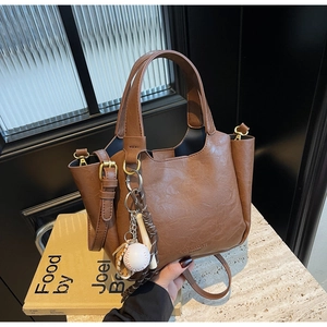 Détail d'un sac seau vintage marron avec pendentif thème baseball et texture en cuir