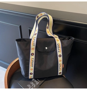 Close-up of black commuter tote bag with floral jacquard handles and silver metal snap button