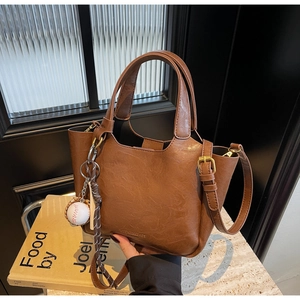 Sac seau en cuir marron avec corde tressée et breloque baseball sur marbre