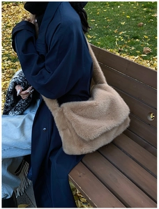 Buitenopname van een camel pluche crossbodytas gedragen bij een donkerblauwe jas