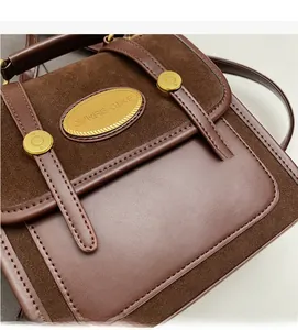 Détail de patchwork en daim et cuir marron avec plaque en métal doré sur le sac à main