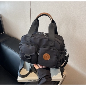 Detail of black canvas crossbody bag with multi-pockets and leather logo patch