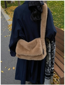 Bruine pluche schoudertas gedragen bij blauwe trenchcoat in een herfstachtig park