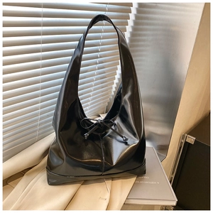 Detailed close-up of glossy black tote bag with bow drawstring and mirror-like finish