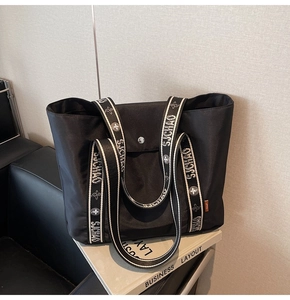 Close-up of black nylon tote bag with SJCHAO woven straps and silver metal snap button