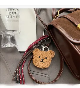 Gros plan d'un pendentif ours en peluche marron avec fermoir argenté sur un sac à main
