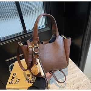 Détail du sac seau vintage marron en similicuir avec un pendentif de baseball ludique