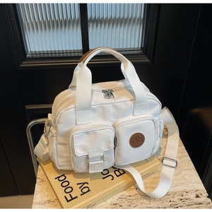 Detailed view of a white nylon crossbody bag with pockets on a marble surface