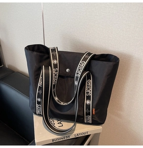 Detail of black nylon tote bag with patterned SJCHAO strap and metal button closure