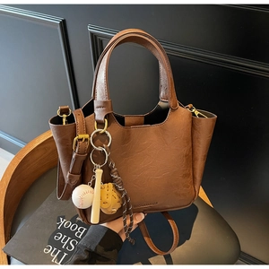 Détail du sac seau vintage en cuir marron avec accessoire de charme de sac thème baseball