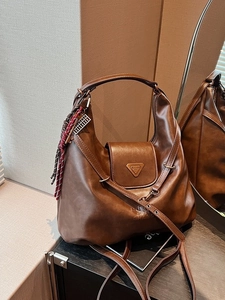 Vintage brown leather hobo bag with adjustable strap and decorative woven pendant