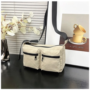 Detail of off-white nylon crossbody bag with dual zip pockets and adjustable strap
