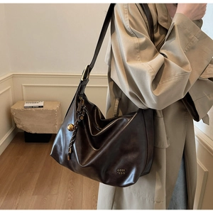 Macro detail of dark brown tote bag showing matte leather texture and vintage gold buckle