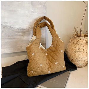 Detailed embroidery of white bears on a khaki quilted shoulder bag with smooth nylon texture