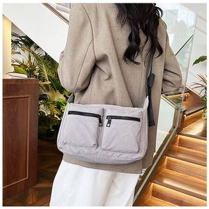 Close-up of lilac nylon crossbody bag with two front zipper pockets and textured fabric