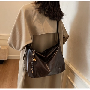 Detail of dark brown leather tote with gold bell charm and COIH '2DN embossed logo