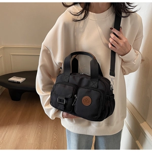 Pratica borsa in nylon nero multitasche mostrata su modella in un ambiente interno