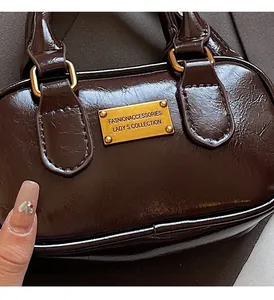 Close-up of a glossy dark brown leather handbag with elegant gold brand nameplate