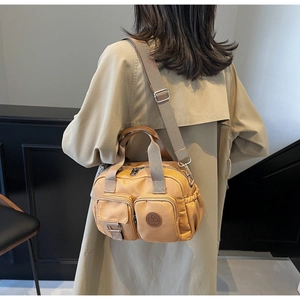 Model wearing a mustard yellow nylon crossbody bag with multi-pockets over a beige trench coat