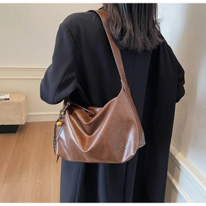 Detail view of large vintage brown tote bag with smooth texture and golden spherical charm