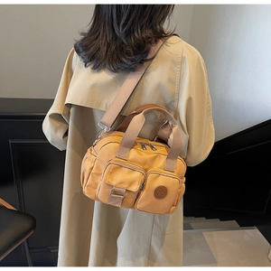 Detailed back view of a yellow nylon shoulder bag with wide strap on a female model