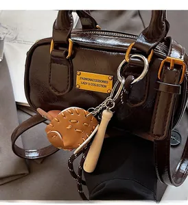 Detail of dark brown oil wax leather handbag with baseball charm and gold hardware