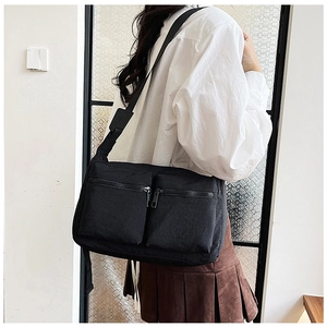 Detailed view of the dual front zipper pockets on this black nylon crossbody shoulder bag