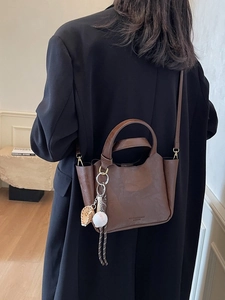 Sac seau rétro caramel avec breloque de baseball porté sur une veste noire
