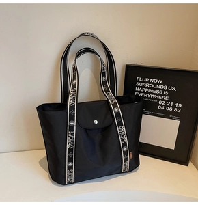 Detail of black tote bag with printed sjchao shoulder straps and silver snap button pocket