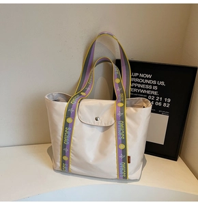 Detail of beige nylon tote bag featuring wide colorful patterned SJCHAO shoulder strap